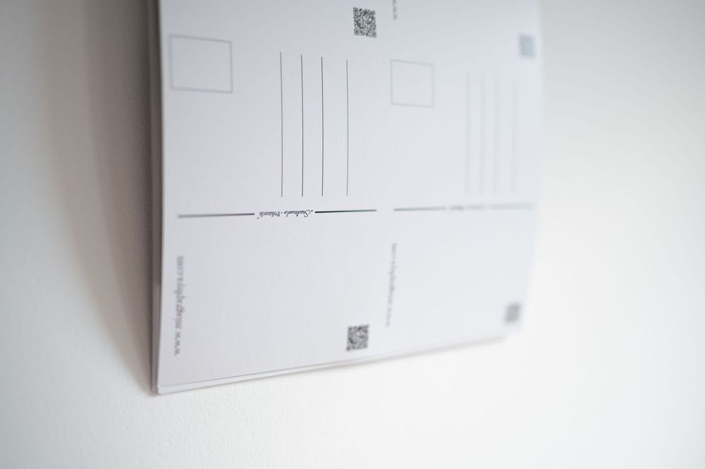 Stack of blank postcards showing reverse side with QR codes, address lines, and stamp box on white background.