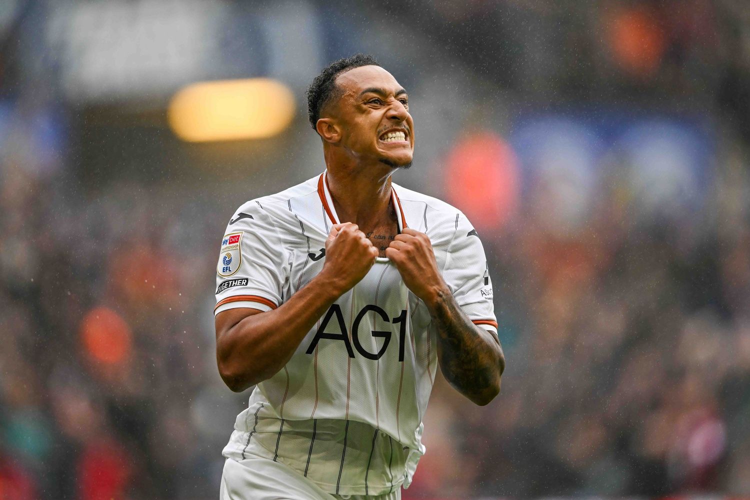 Swansea City footballer wearing white Joma kit with AON sponsor, number 17, running during a match.