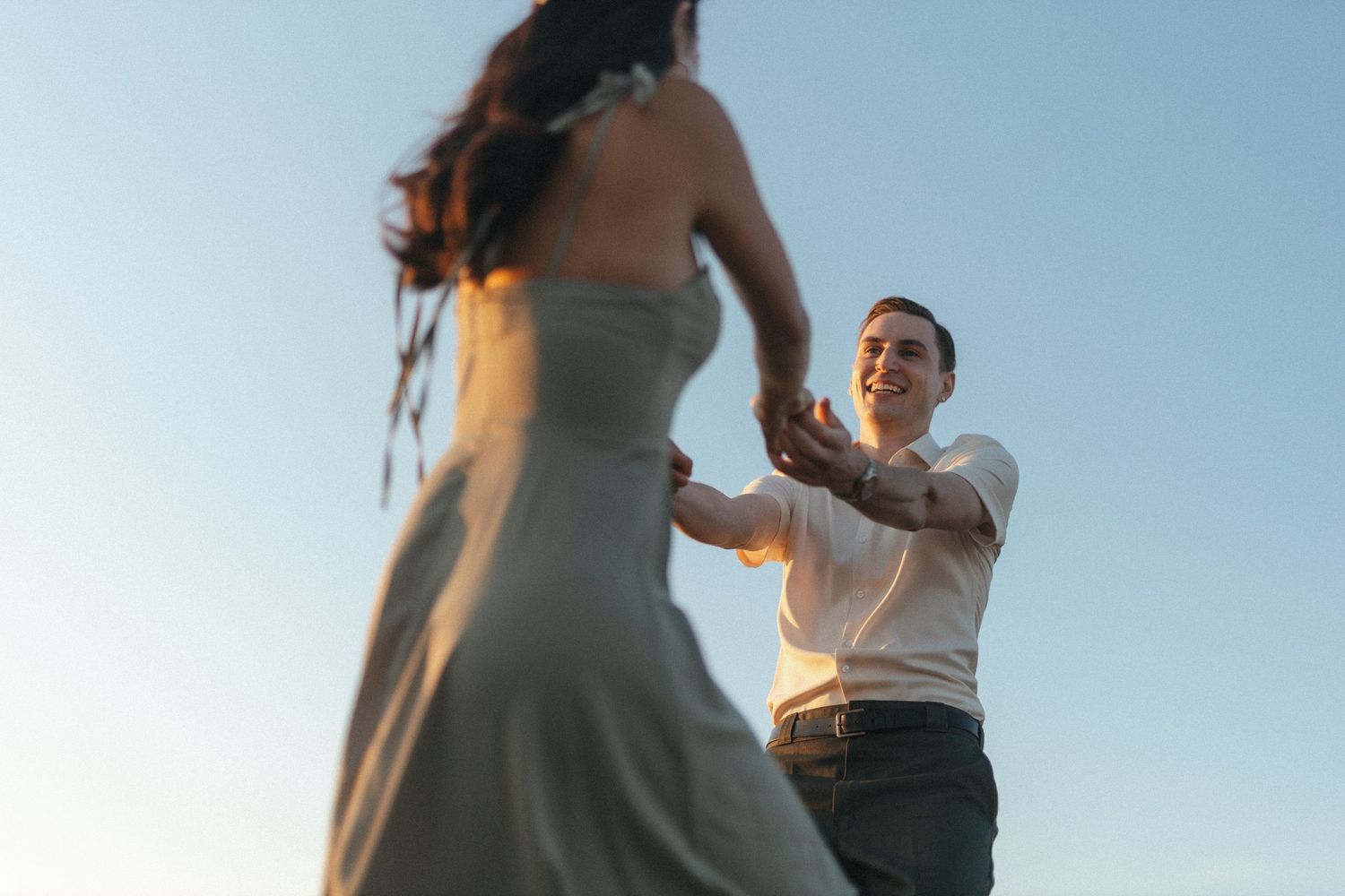 bride and groom laugh and spin around against a blue sky during vancouver island elopement