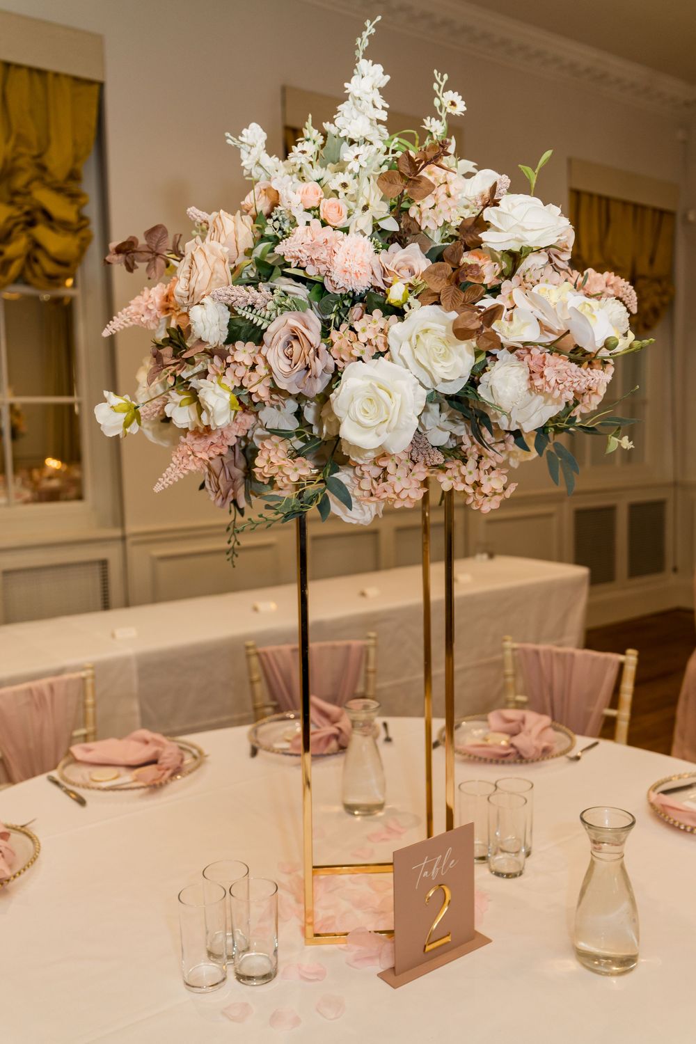 Elegant tall gold wedding centerpiece with blush and white flowers at Table 2.