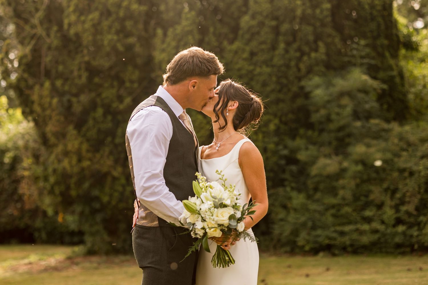 Wedding dress train flows dramatically against an ivy-covered brick wall background.