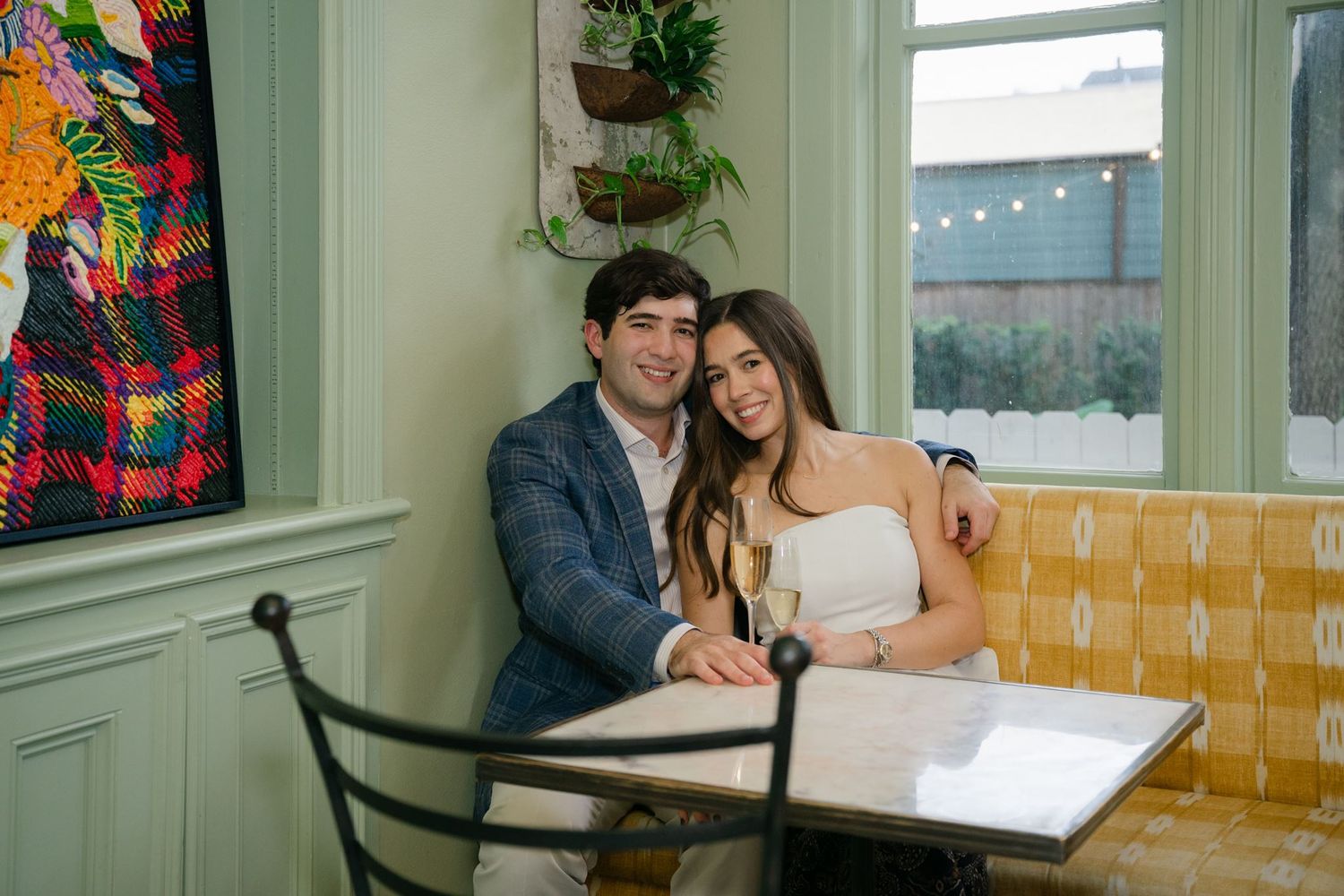 Newly engaged couple sitting in the sunroom of The Marlene hotel.