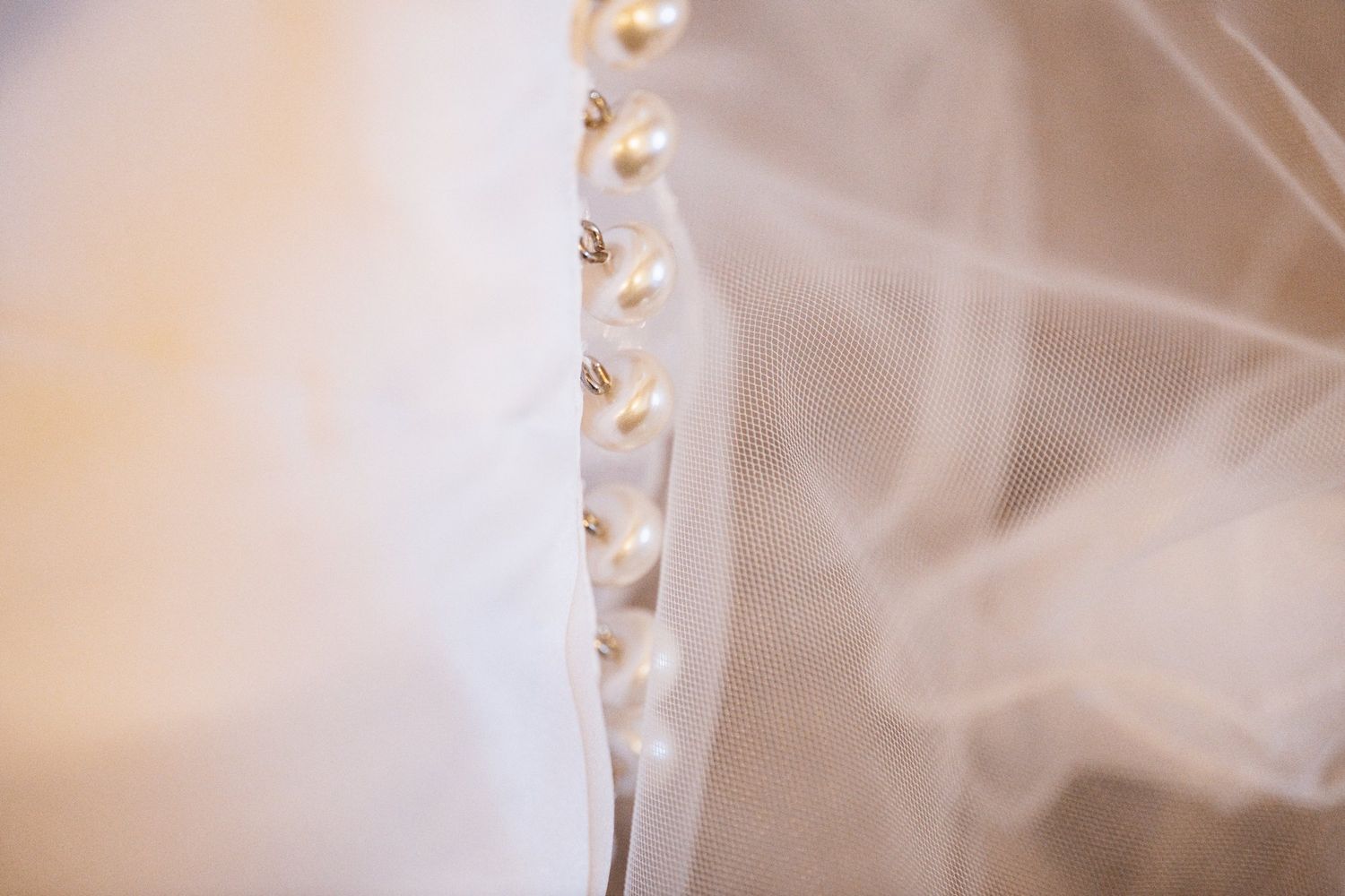 Pearl buttons down the back of the bride's dress beside her veil, Sandhole Oak Barn wedding