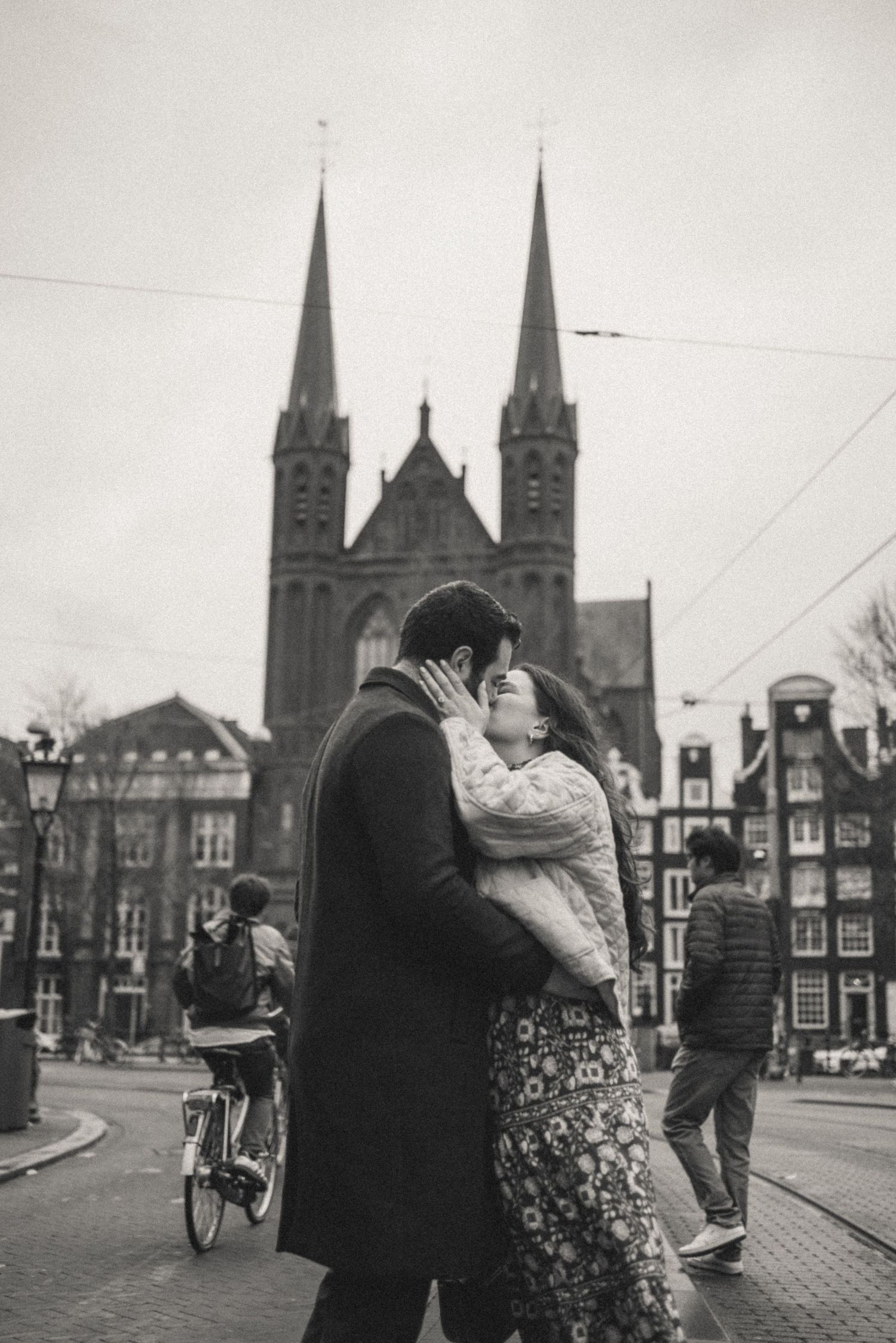 Couple kissing on a European city street in black and white with a Gothic church, Spui, Amsterdam.