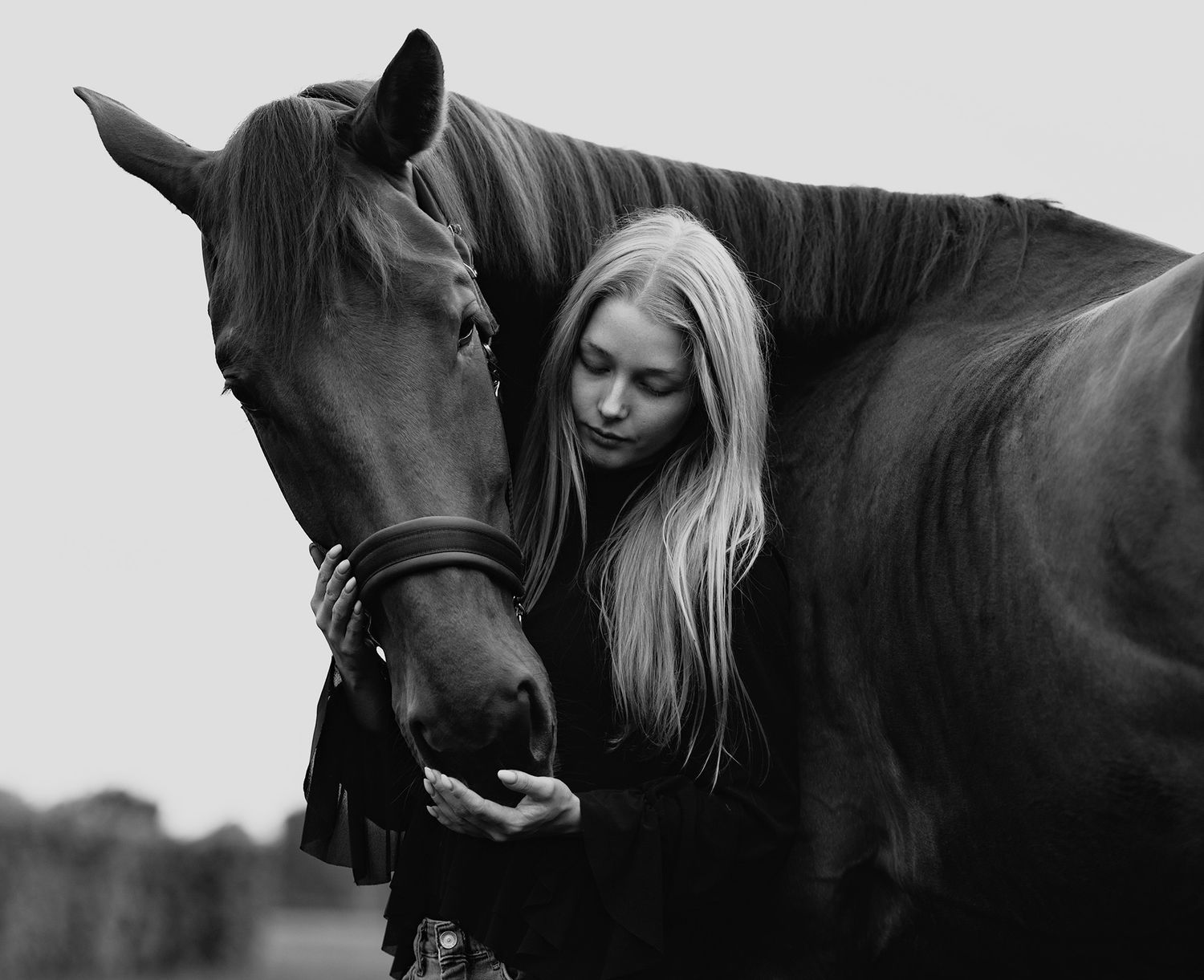 Tijdloos zwart-wit portret van een vrouw met haar paard tijdens een paardenfotoshoot.