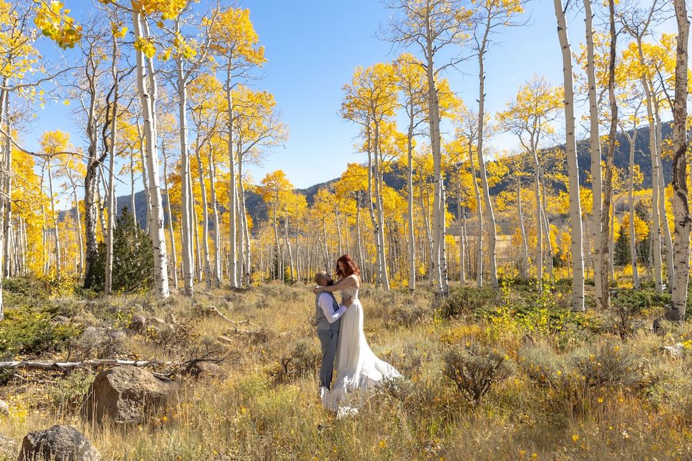 Couple embracing in a golden aspen forest during fall wedding in Colorado mountains.