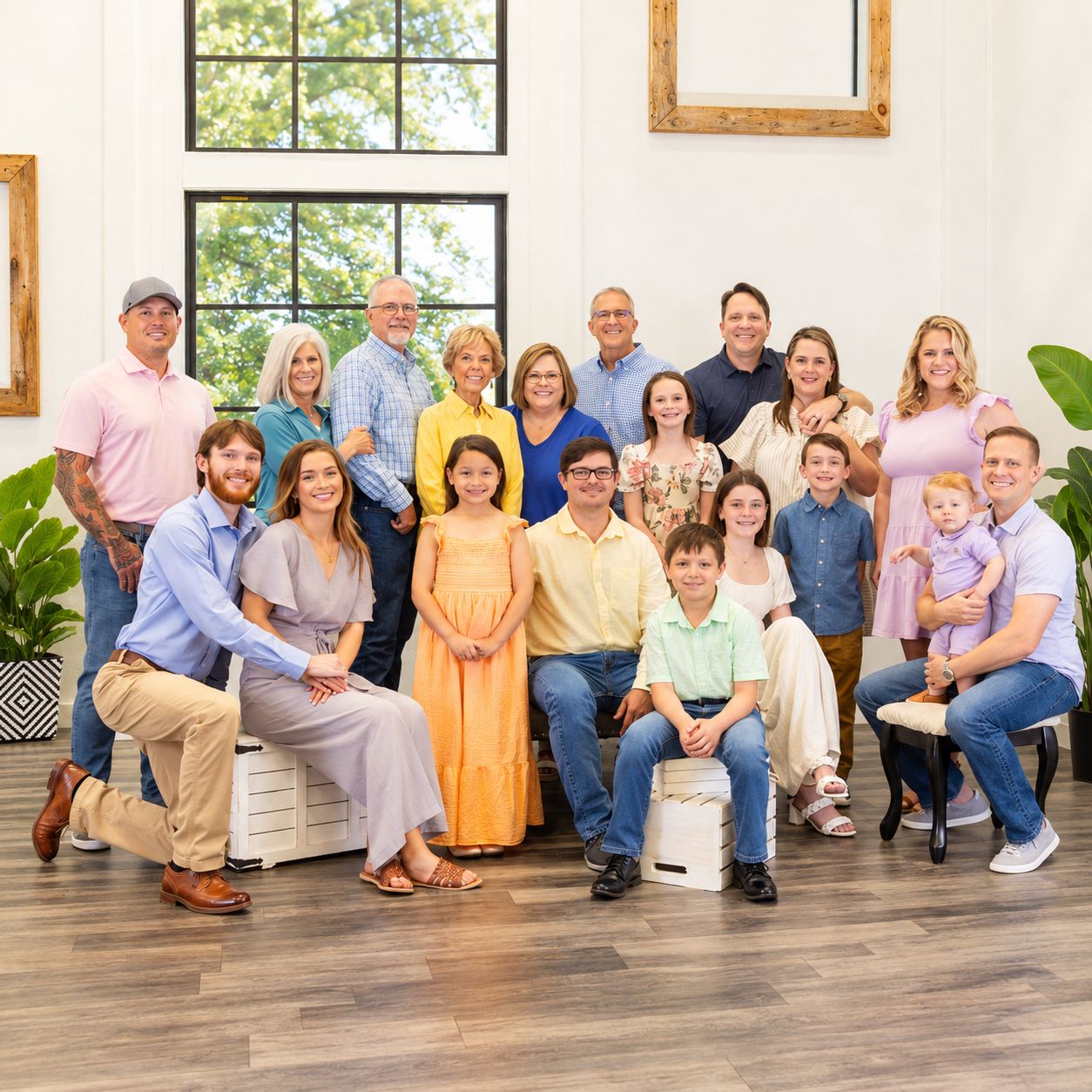 Large multigenerational family group portrait smiling together in a bright modern white interior space.