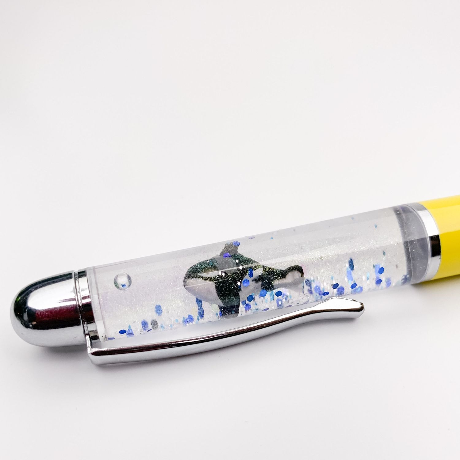 Blue and silver floating glitter pen with a clear barrel filled with liquid, blue star charms, and colorful sparkles.