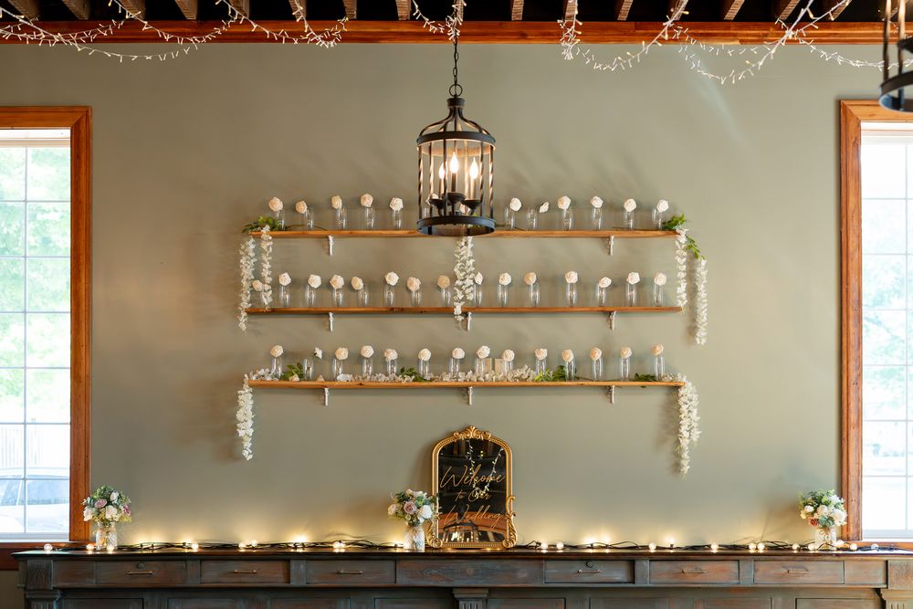 Elegant wedding display with gold shelves holding glass vases, fairy lights, and a vintage birdcage pendant light.
