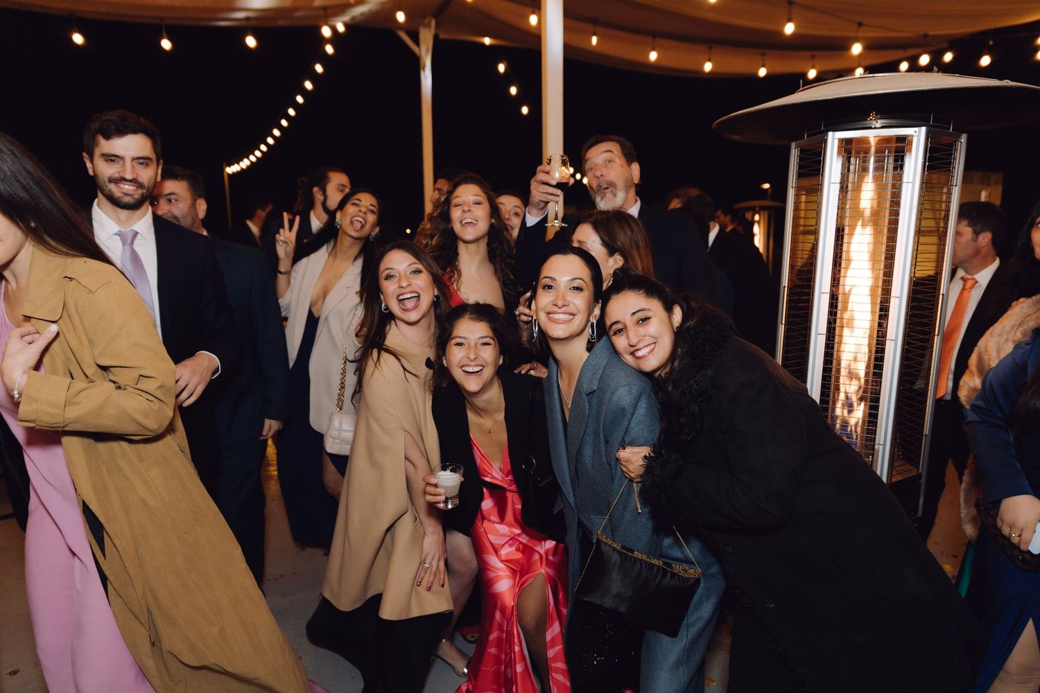 Smiling group of women posing together at an outdoor evening wedding reception celebration.