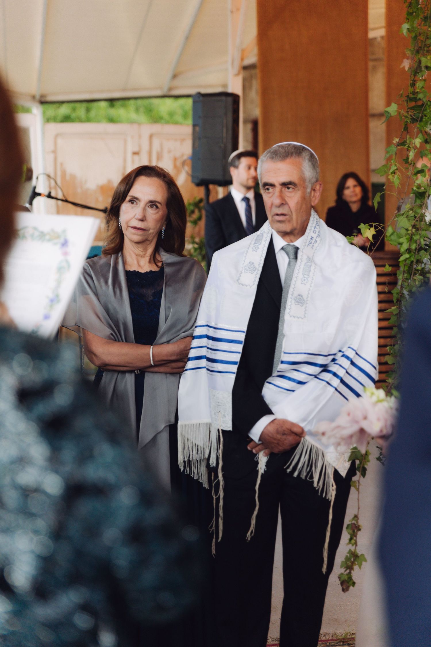 Man wearing a tallit stands with a woman beside him during a Jewish wedding ceremony.
