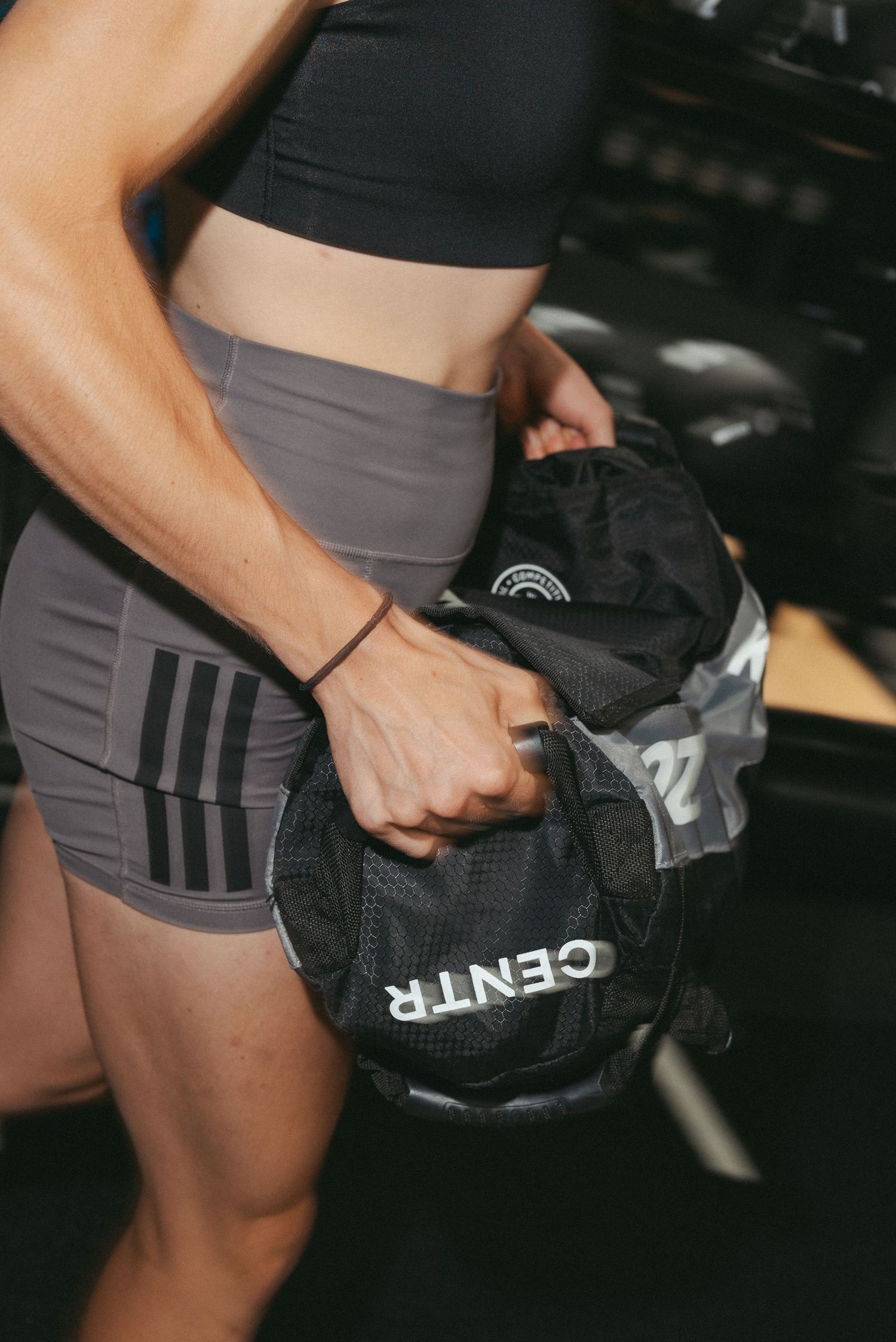 Fit woman holding a Centr branded medicine ball during a gym workout session.