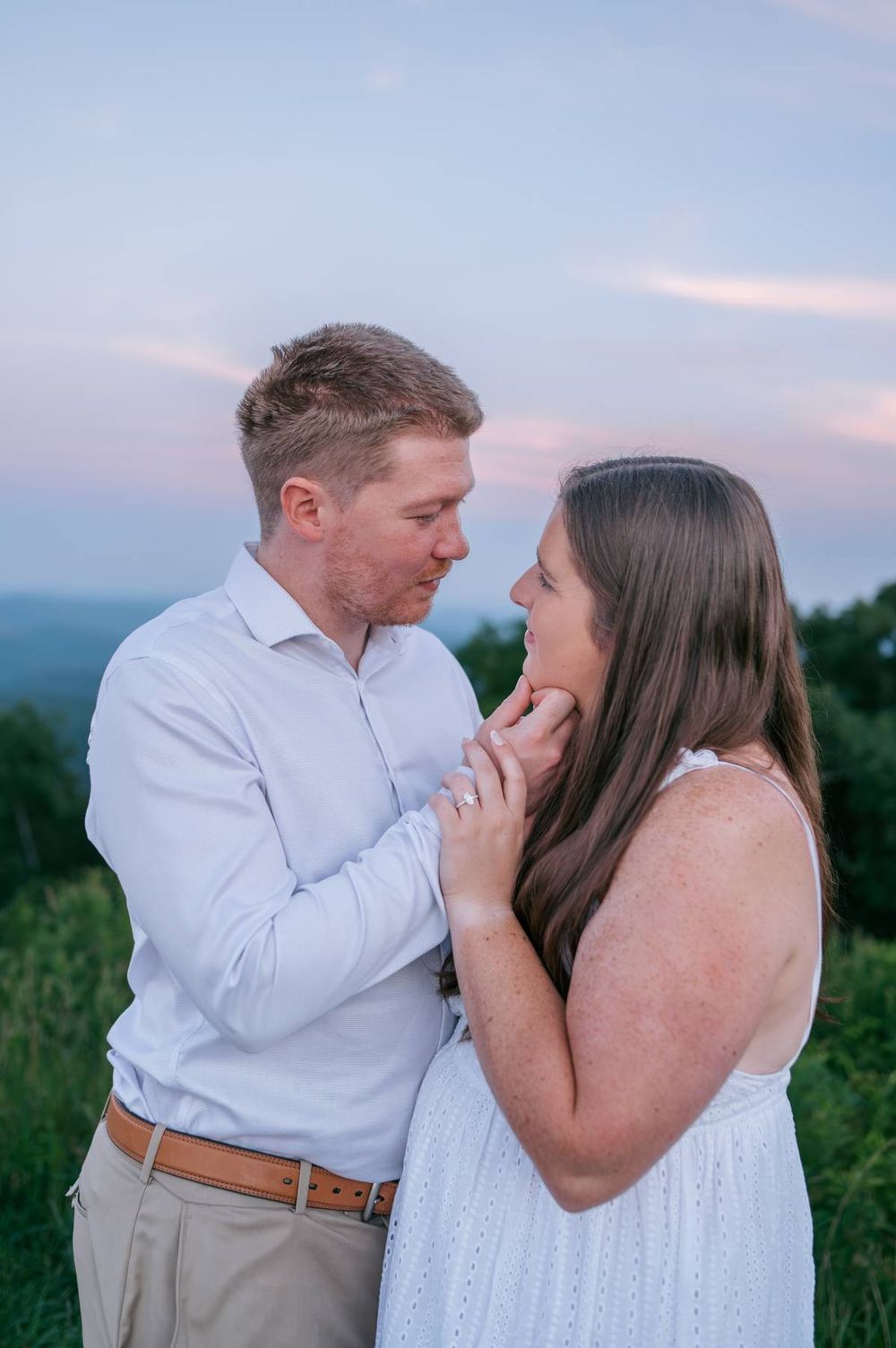 Romantic couple gazing at each other at dusk with scenic mountain views behind them, engagement photographer in Greensboro, NC