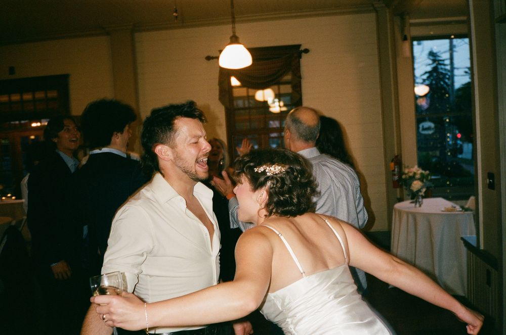 Joyful couple dancing together at wedding reception in warmly lit intimate venue.