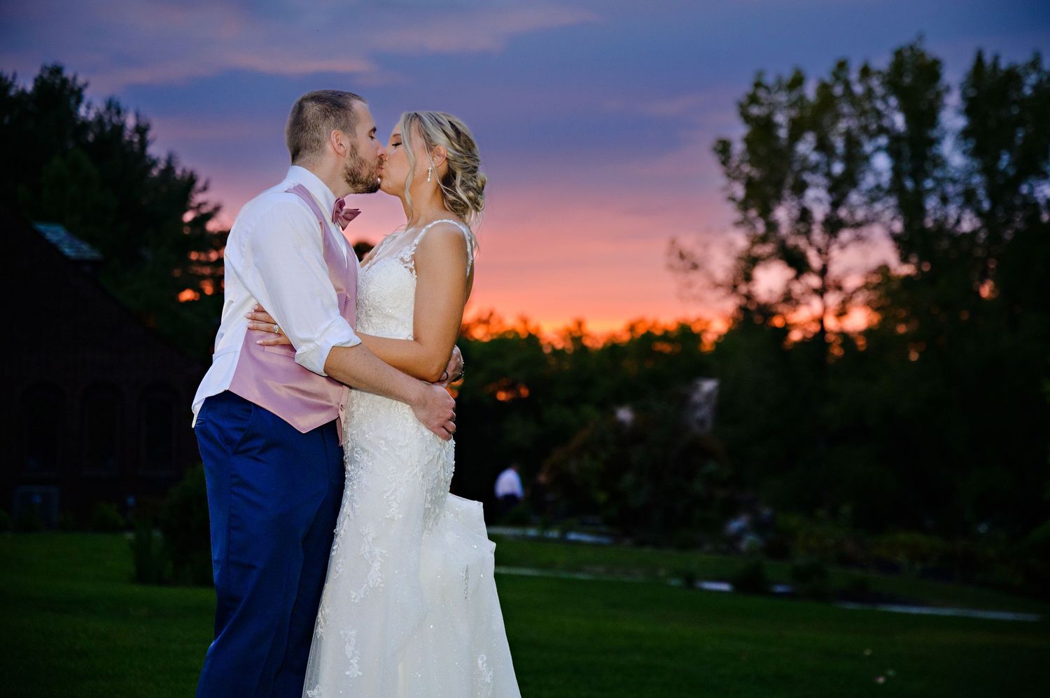 Bride and groom kissing in front of a sunset during their wedding reception at Tudor House at Mason's Cove on Portage Lakes in Akron Ohio