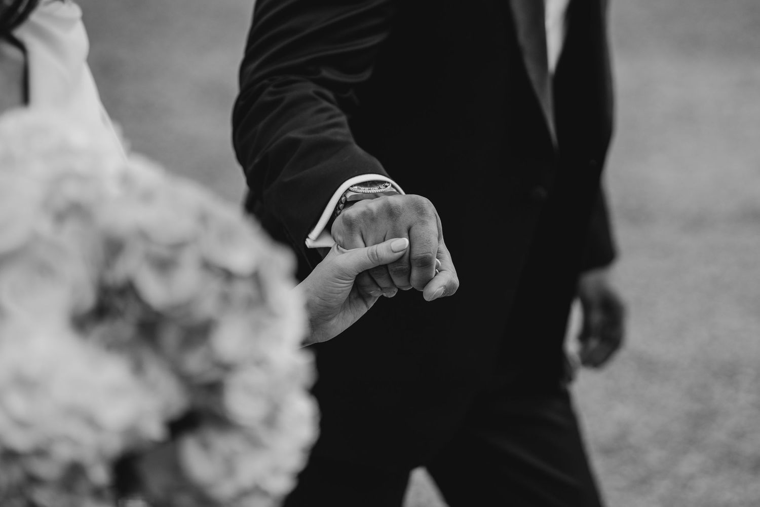 A black and white photo shows people's legs and feet walking on a stone or concrete surface.