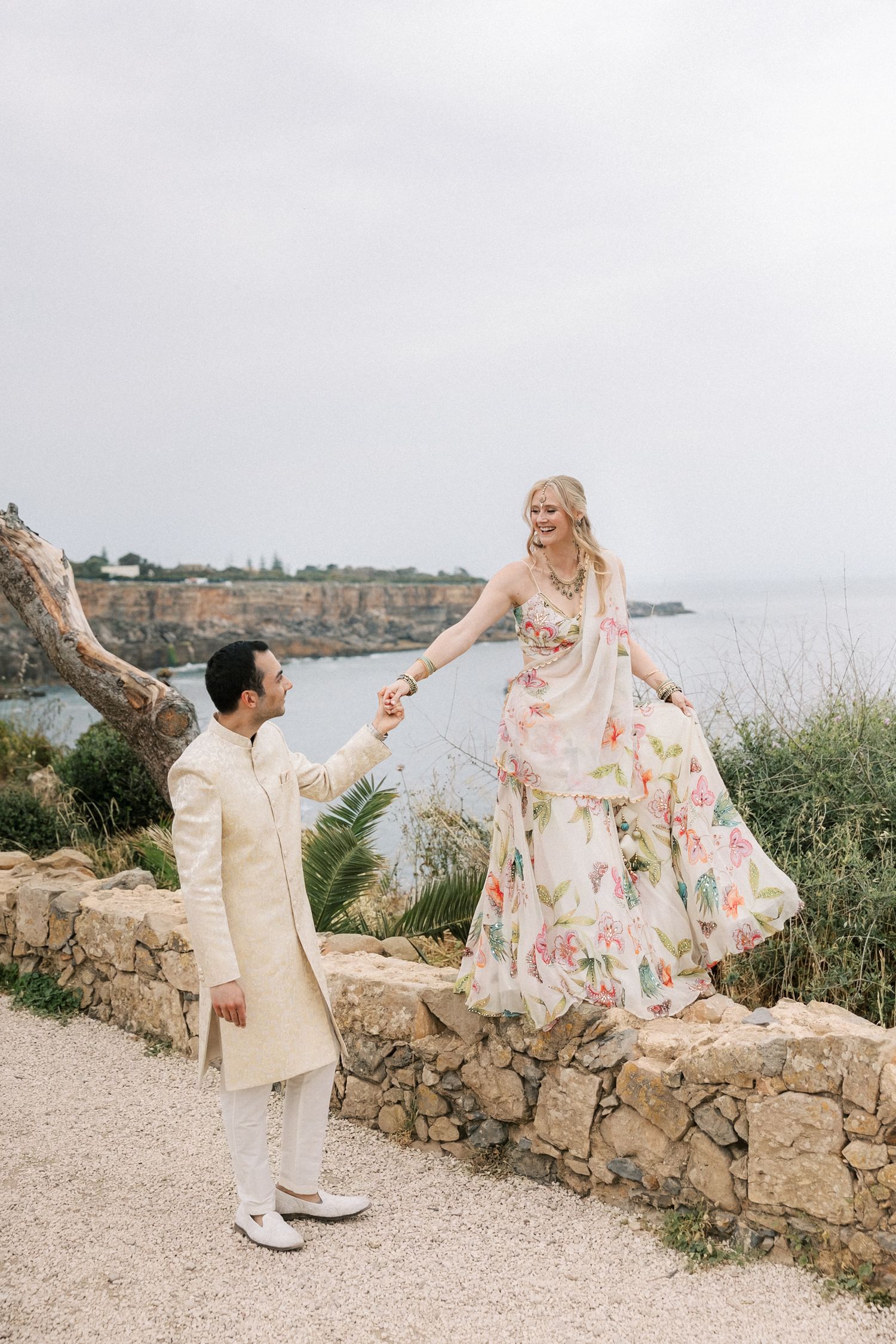 Bride and groom wearing elegant Indian wedding attire during their seaside Mehndi portrait session in Cascais, Portugal.