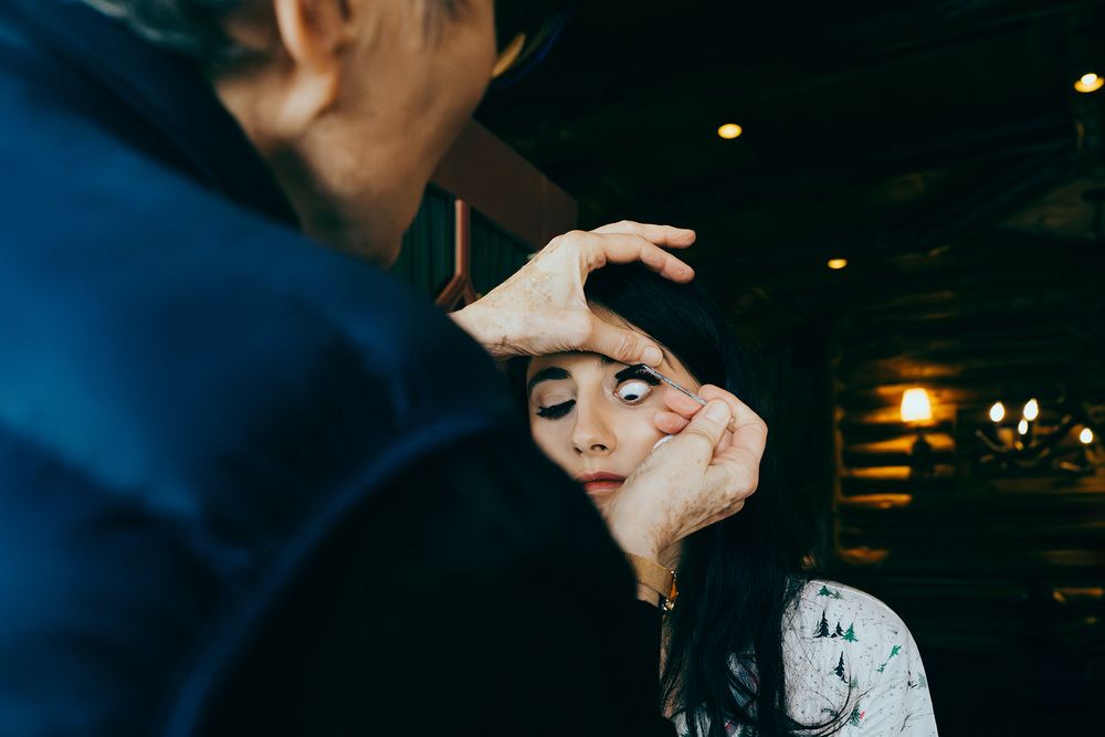 A person frames another's face with their hands in a dimly lit restaurant setting.