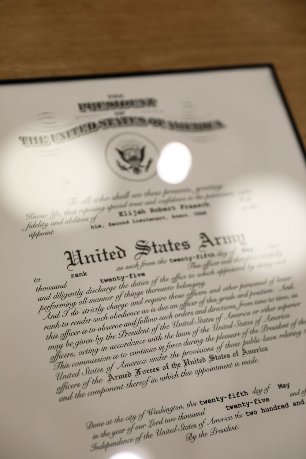 United States Army commission certificate framed on a wooden surface, official military appointment document.