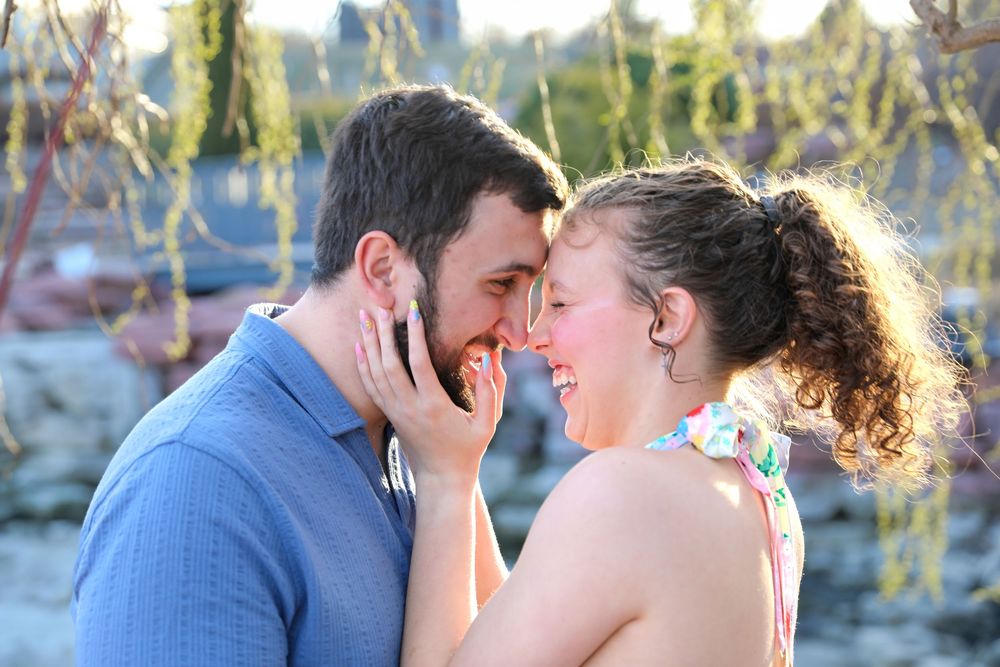 Romantic couple sharing an intimate moment outdoors, touching foreheads and smiling, with a blurred garden background.