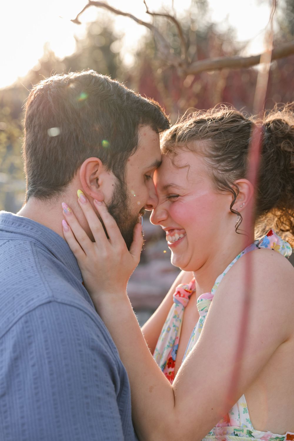 A joyful couple sharing an intimate moment outdoors, laughing together in warm golden sunlight.