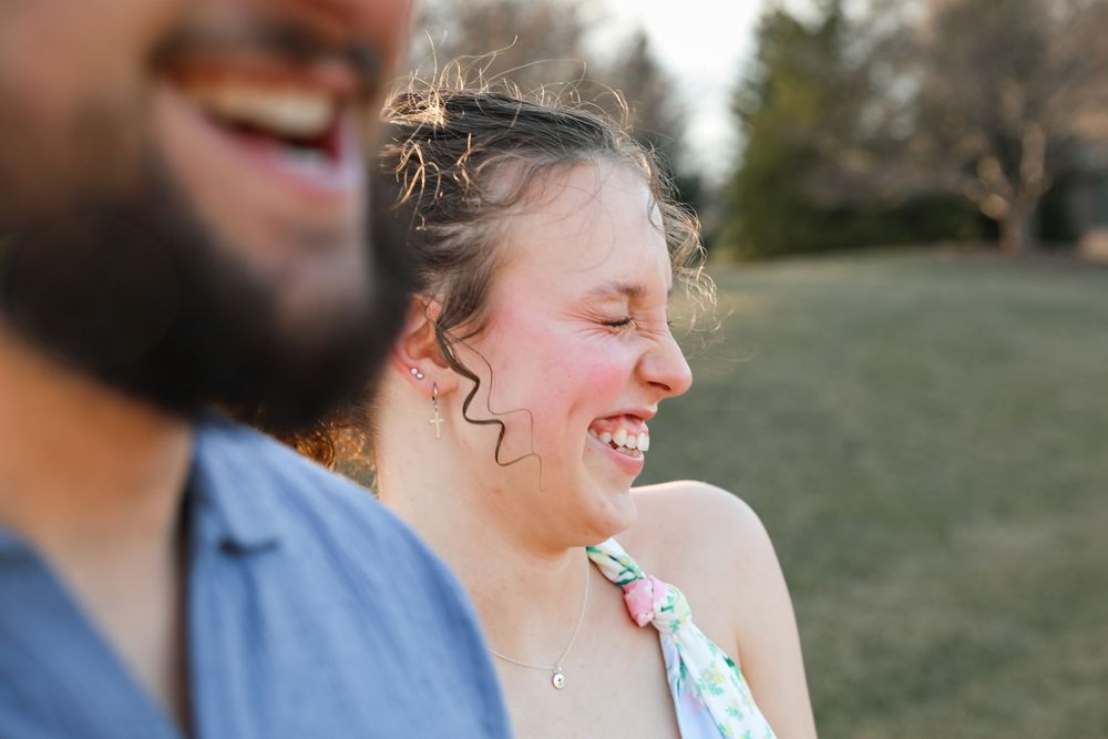 Two people laughing joyfully outdoors in a park, sharing a candid and happy moment together.