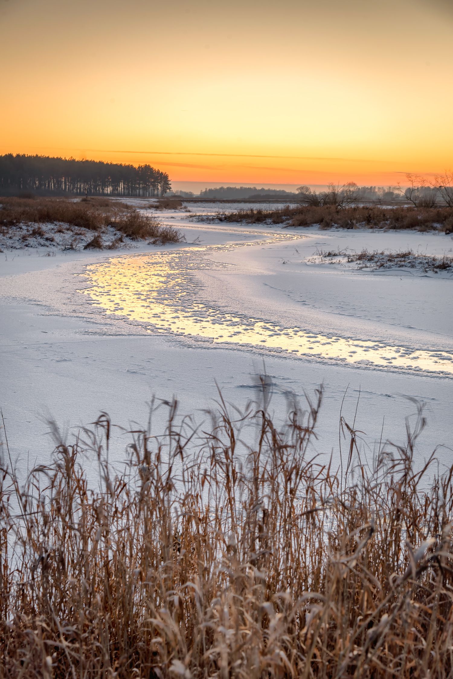 Fiume ghiacciato che riflette i colori arancioni del tramonto