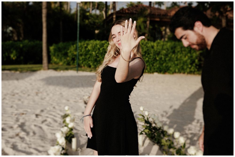 Bride showing engagement ring during a destination engagement session at The St. Regis Punta Mita with floral details and beach.
