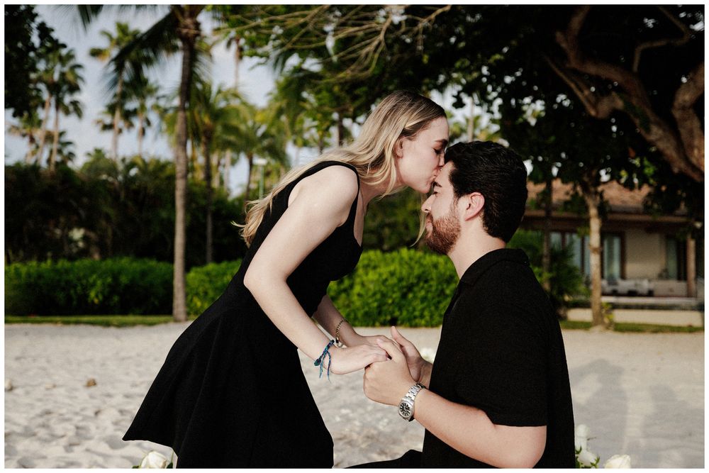 Couple celebrating a beach proposal during a destination engagement session in Mexico with palm trees and tropical surroundings.