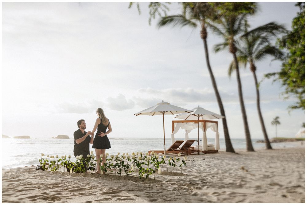 Romantic beach proposal during a luxury engagement session in Mexico with floral details, palm trees, and ocean views.
