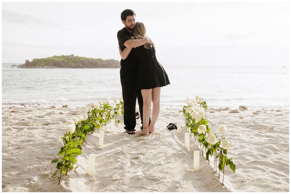 Couple embracing during a romantic proposal at The St. Regis Punta Mita with floral details, candles, and oceanfront beach setting.