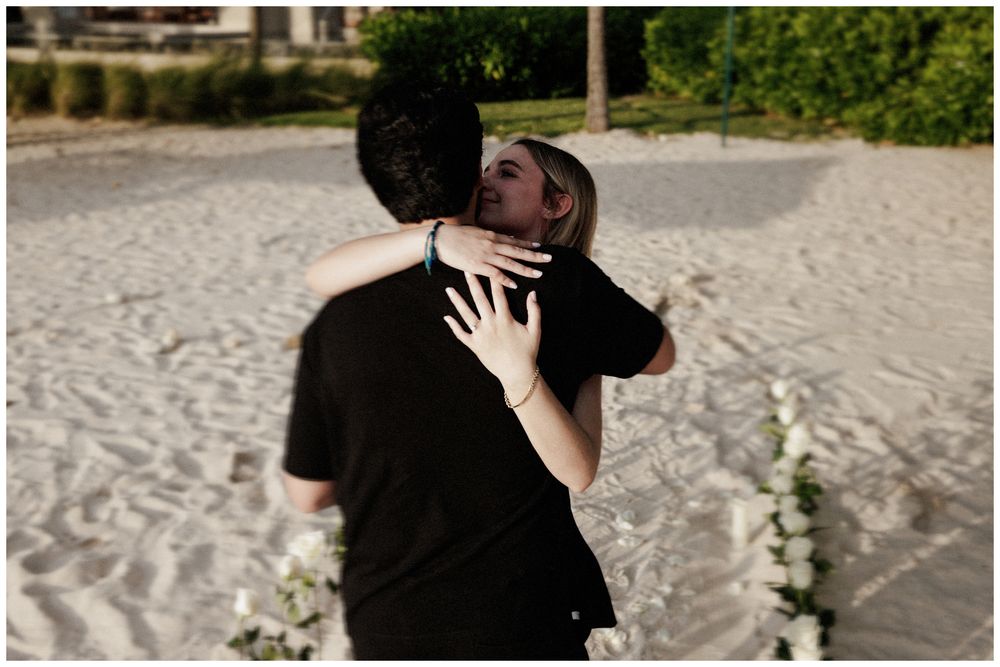Couple embracing and kissing on a sandy beach at The St. Regis Punta Mita during a destination engagement session.