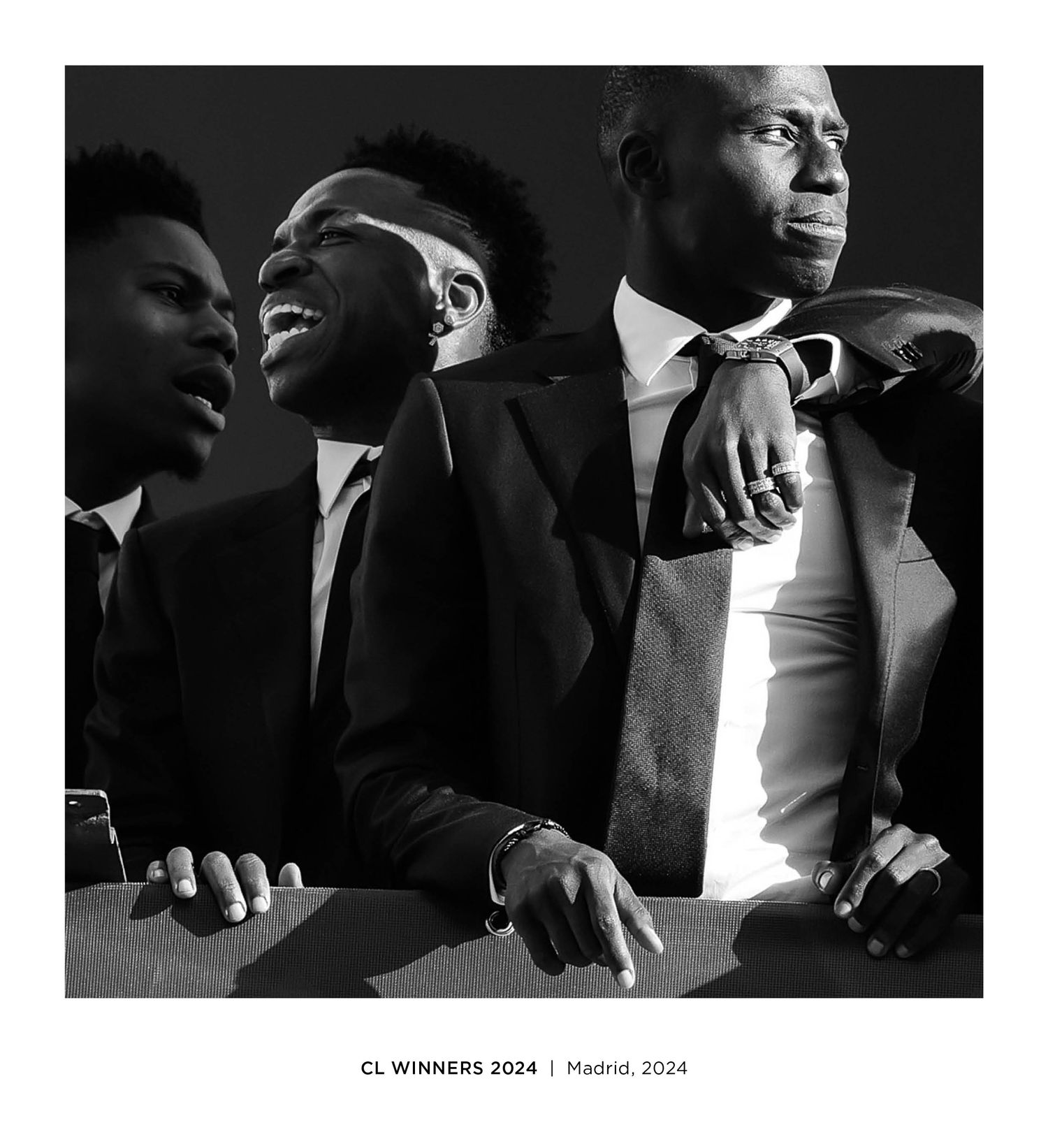 Three men in suits celebrate as CL Winners 2024 in Madrid, captured in a dramatic black and white portrait.