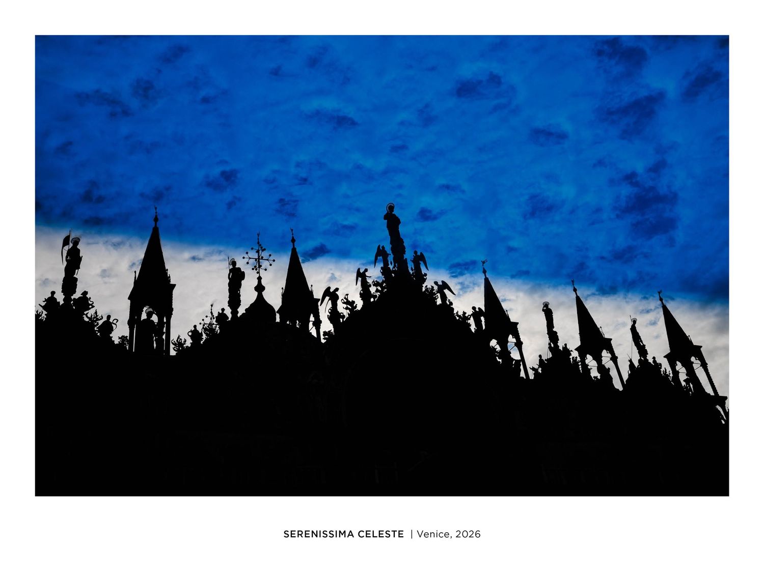 Silhouette of Venice skyline with spires against a dramatic blue sky, titled Serenissima Celeste, Venice 2024.