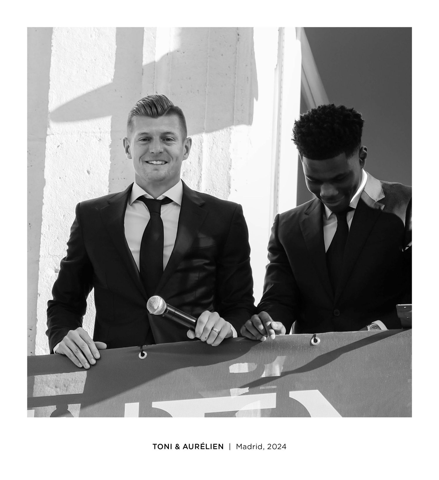 Two men in suits smiling on a balcony in Madrid, 2024, labeled Toni and Aurelien.