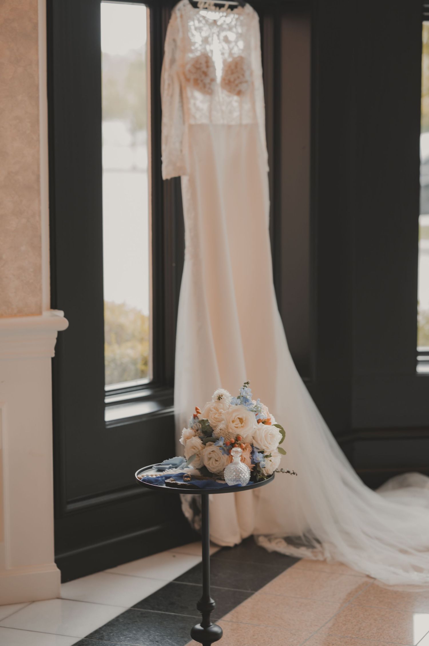 Elegant white bridal heels with lace detail and wedding rings resting on heel, sepia-toned wedding photography.