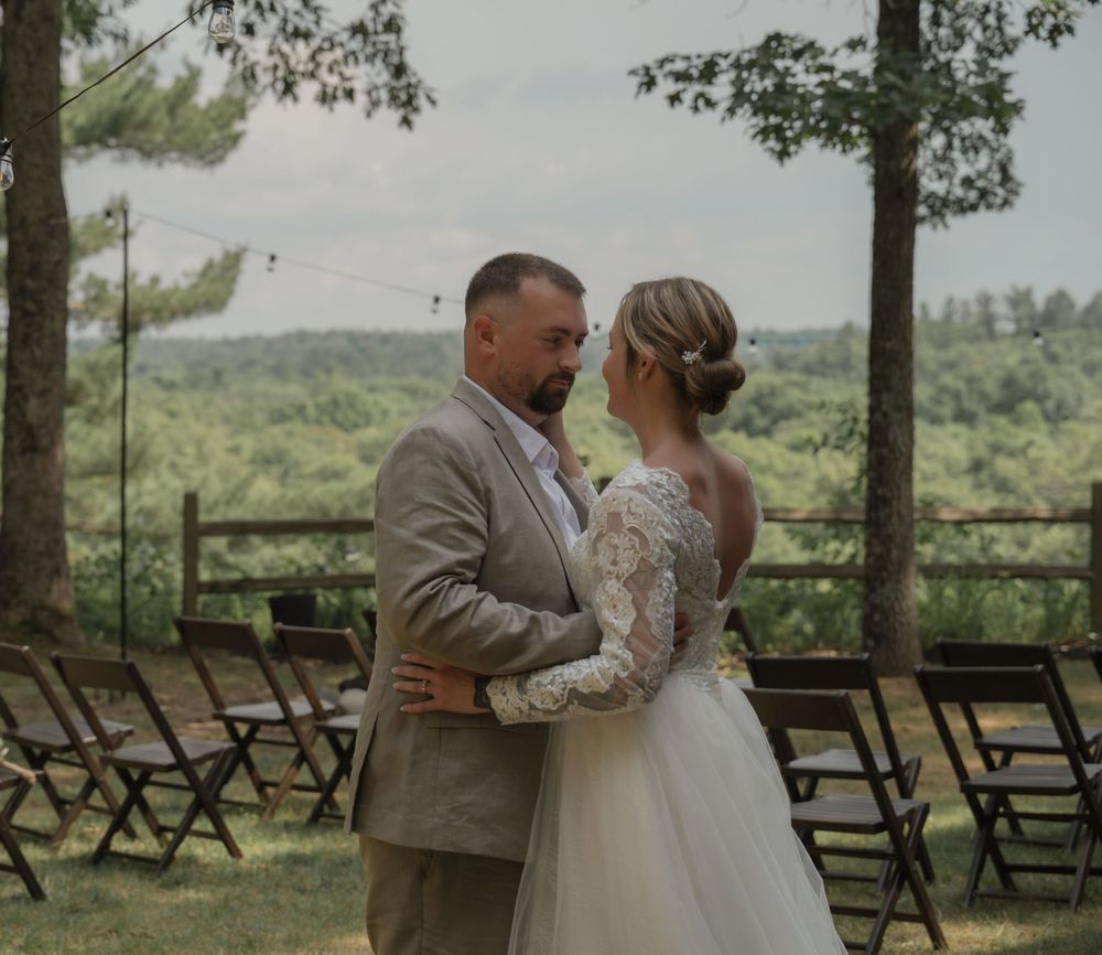 Bride and groom share a romantic first dance outdoors at a rustic woodland wedding venue.