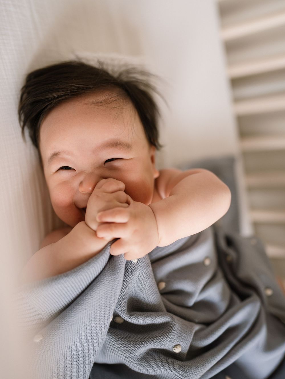 Baby in gray clothing rests while being photographed from different angles.