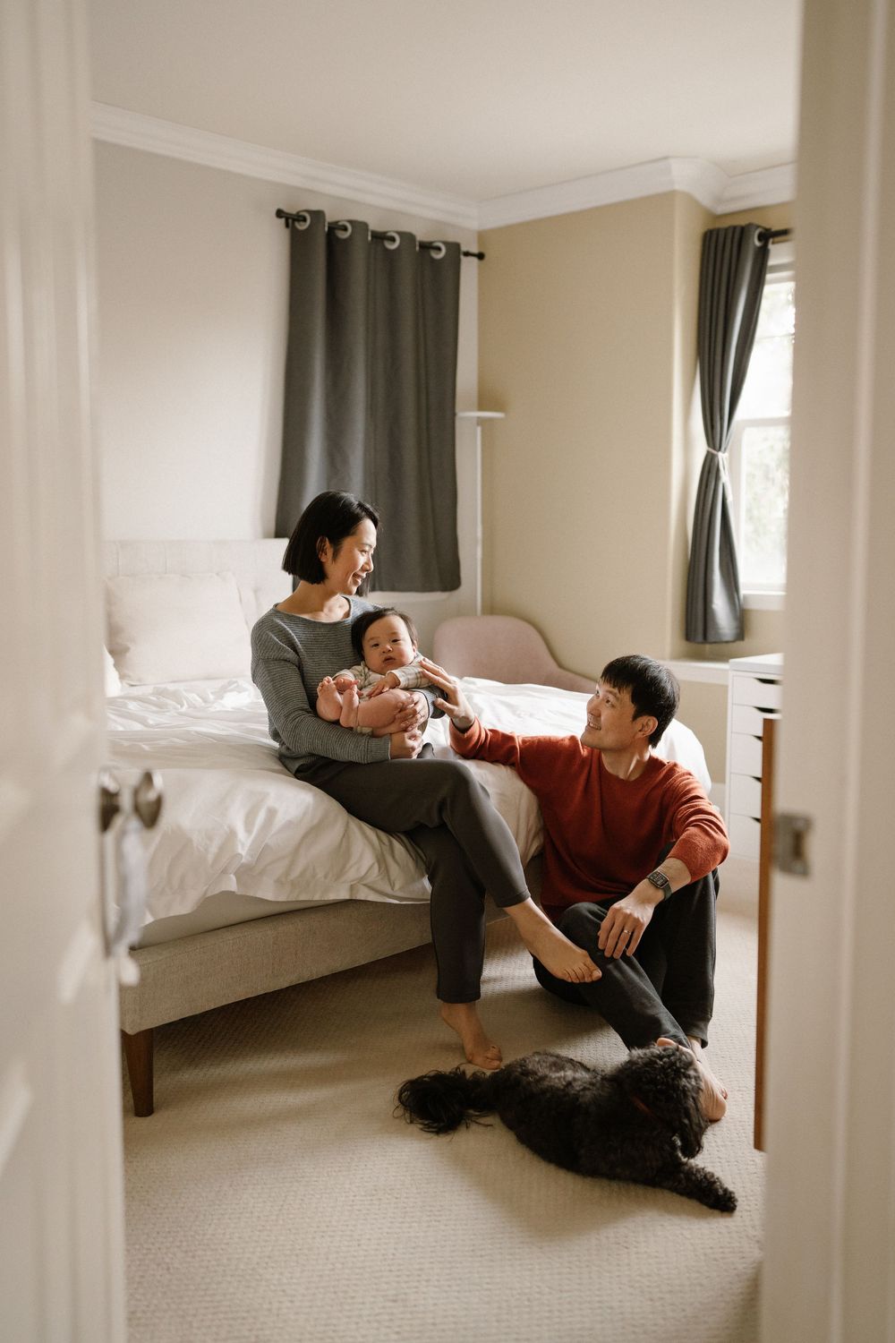 A couple relaxes together on the floor of a bright, modern bedroom.