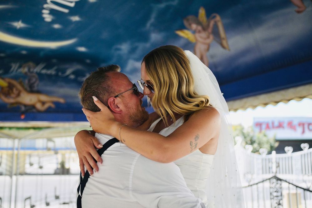 Emotional bride and groom sharing tender kiss under decorated wedding chapel canopy.