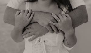 Black and white close-up of a couple embracing, with mans arms wrapped around womans waist.