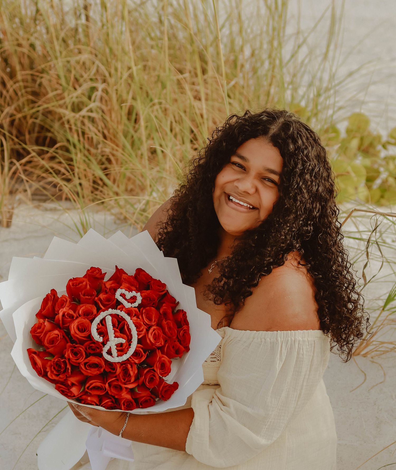 portrait of a woman on a beach holding flowers