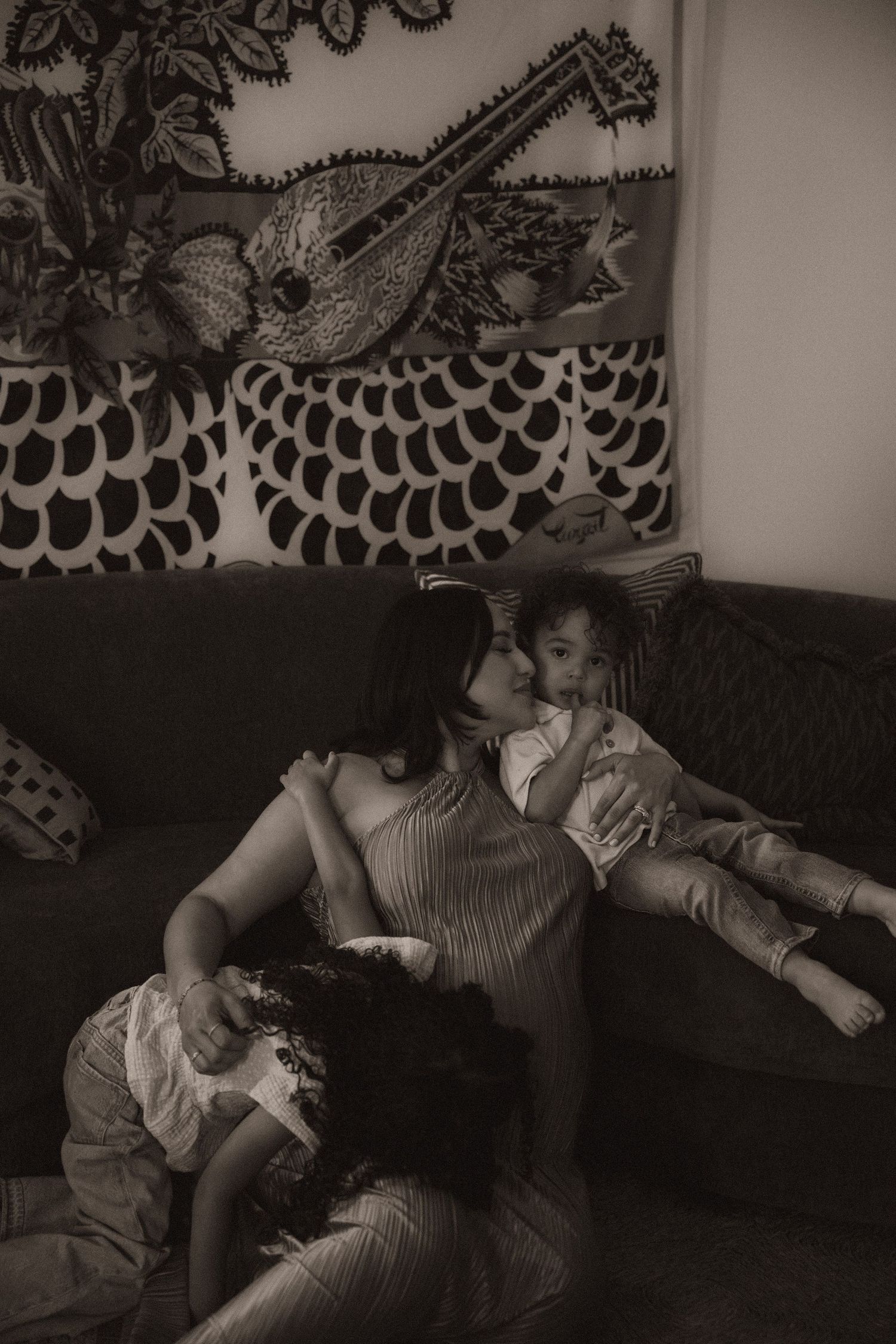 Black and white photo of a mother kissing her baby on a couch during their orange county family photo session.