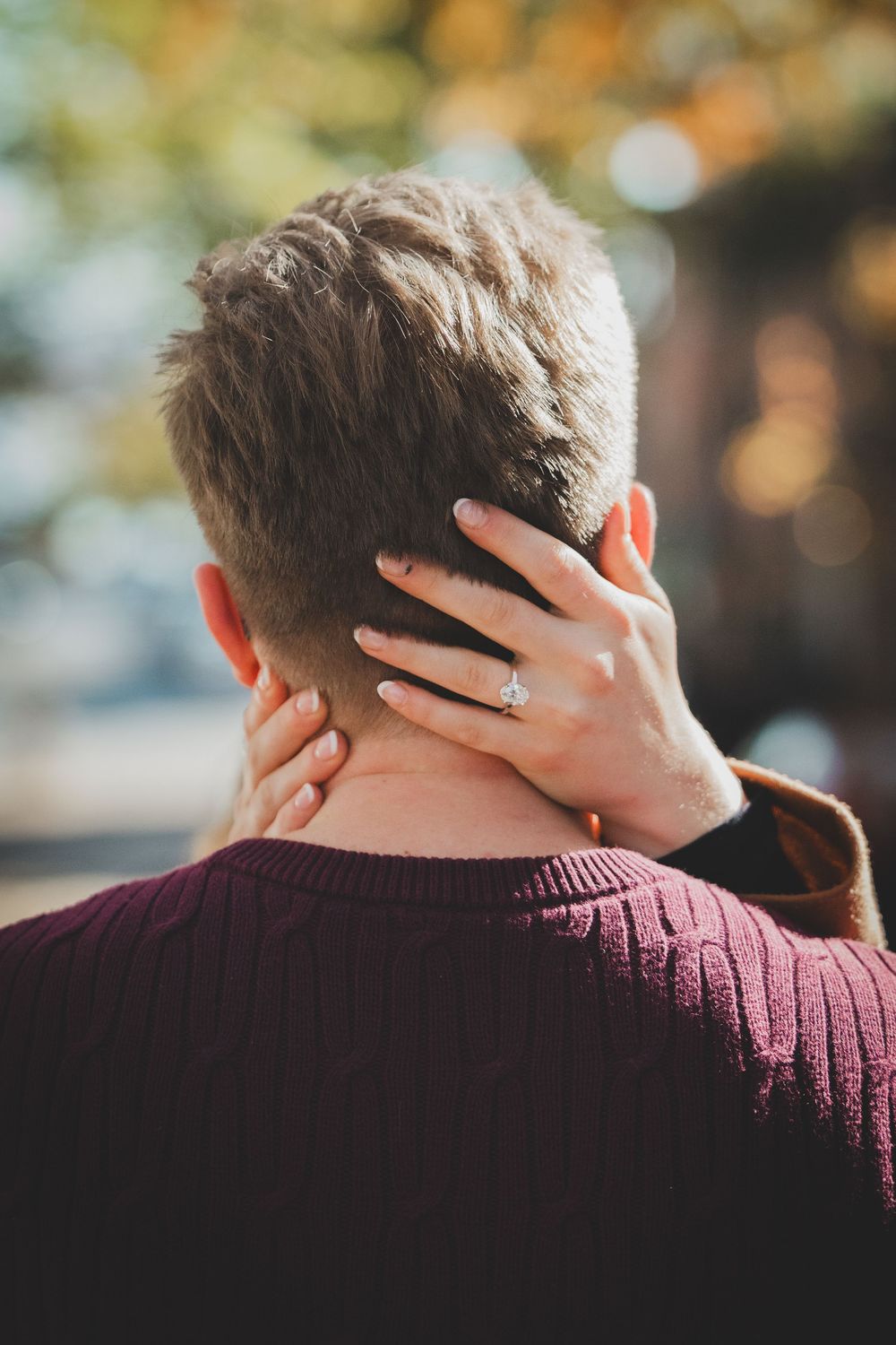 Engagement ring detail on bride-to-be's hand resting gently on groom's shoulder after Old Town Alexandria surprise proposal