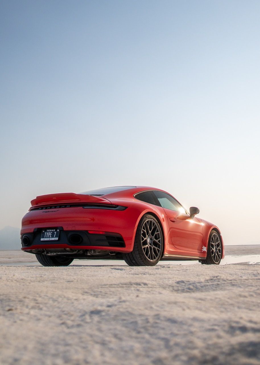 Red Porsche 911 Turbo S rear view on Bonneville Salt Flats under a clear sky.