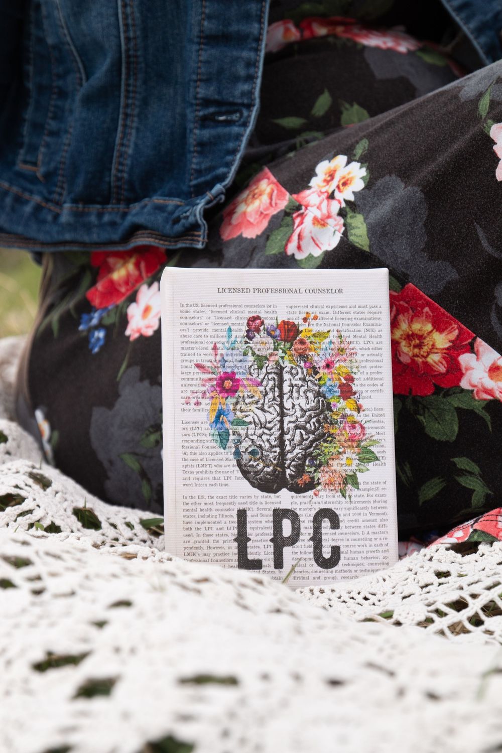 An artistic book page displays a colorful brain illustration with flowers on white lace.