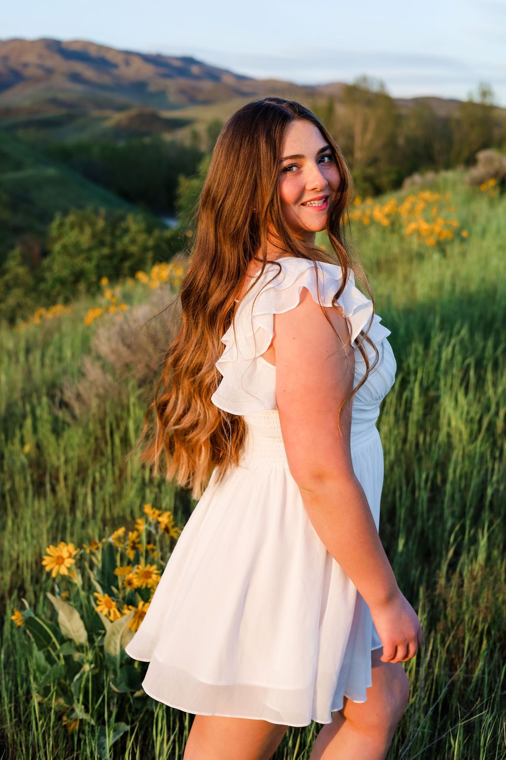 A summer portrait session among wildflowers with mountains in the background.