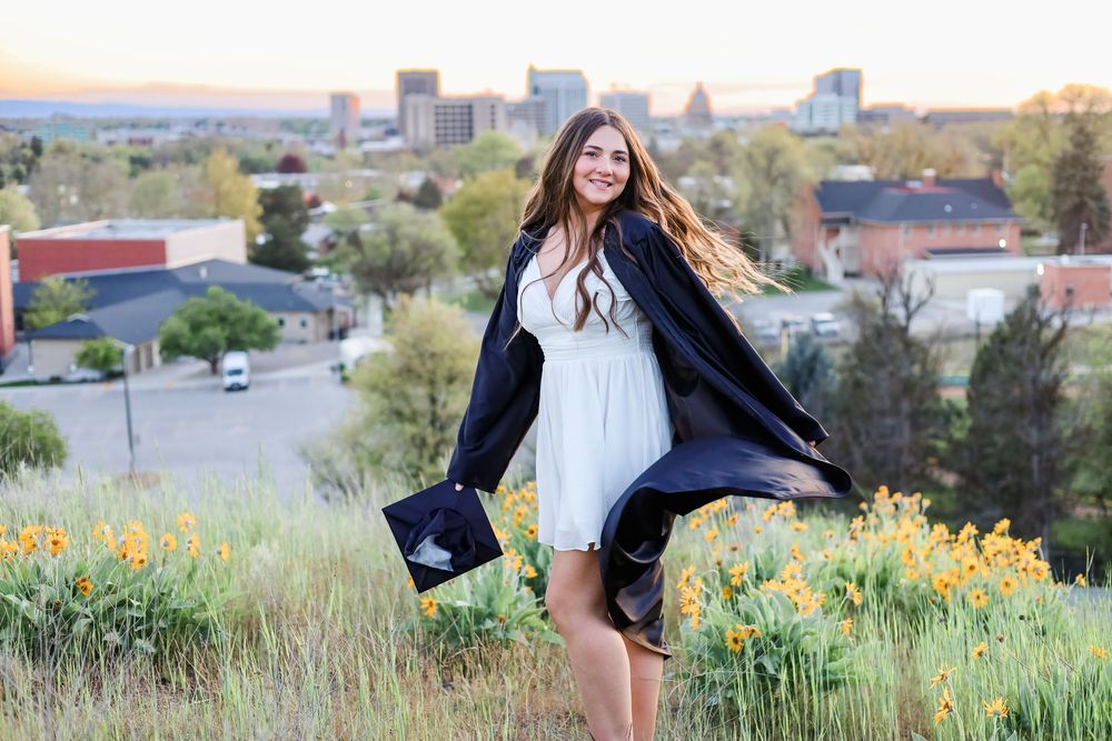 An outdoor senior portrait session with city buildings visible in the distance.