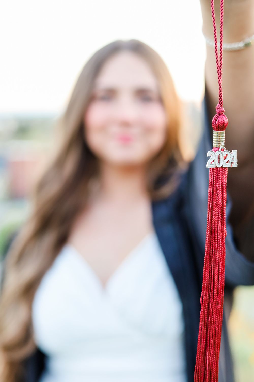 A graduation photoshoot featuring a red tassel against a blurred background.