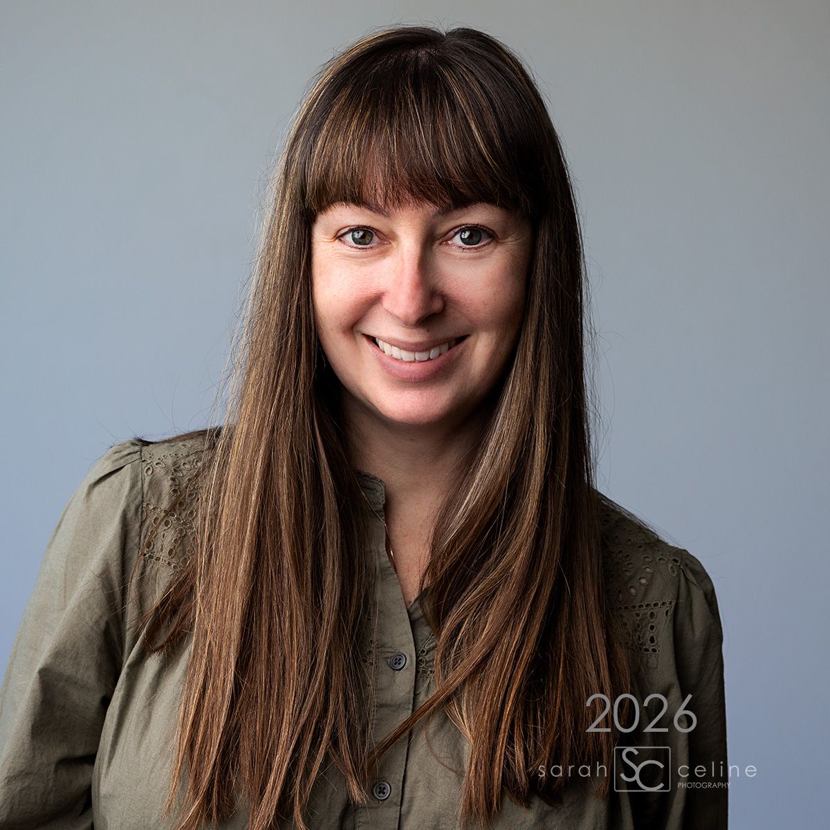 Professional studio portrait against brick wall background in dramatic lighting.